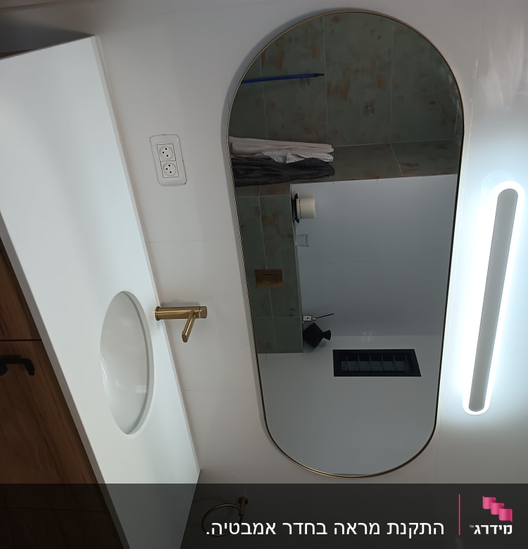 כיור עם ברז זהב ומראה בחדר אמבטיה